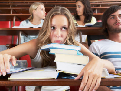 a college student with head on education textbooks