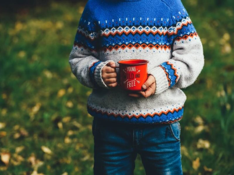 person holding a red mug while wearing a holiday sweater