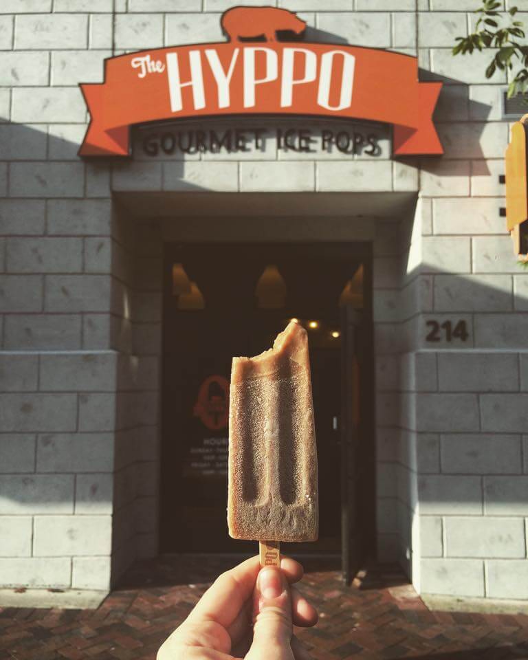 A hand holds up a Hyppo popsicle in front of the store's front door in Gainesville. 