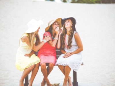 sorority girls in sundresses and hats sitting and laughing together