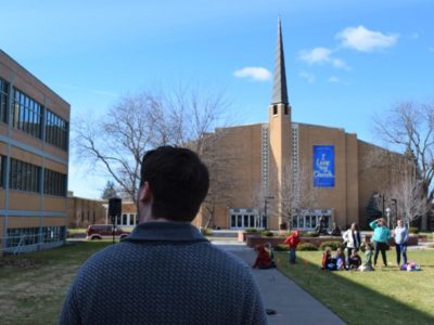 The associate dean of men walking past Kretschmar Hall toward the University Church at Walla Walla University