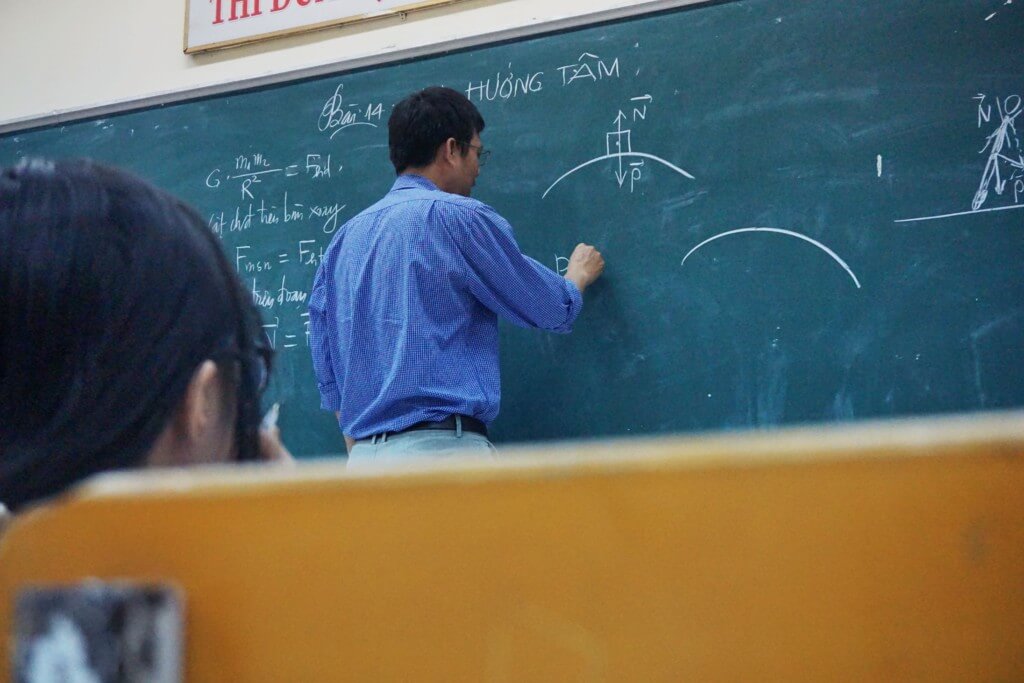 professor writing on chalk board 