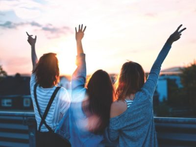 three girls staring at the sun and throwing peace signs