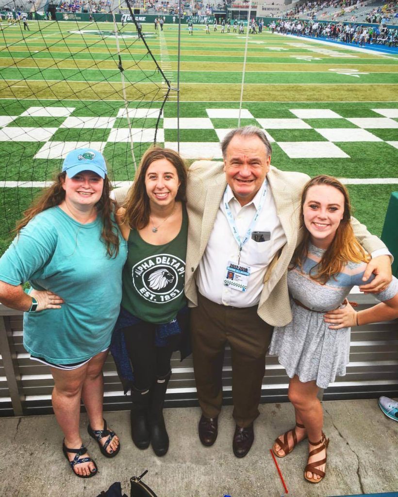 three girls and Tulane president Mike Fitts at a Tulane football game