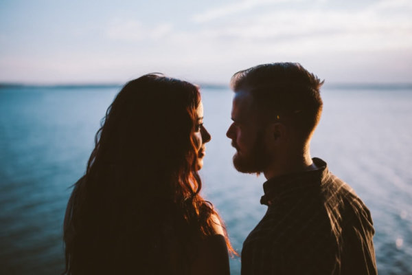 How to ask a shy guy out- woman and man staring at each other by open water.