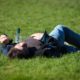 man passed out in a field with a bottle of vodka next to him