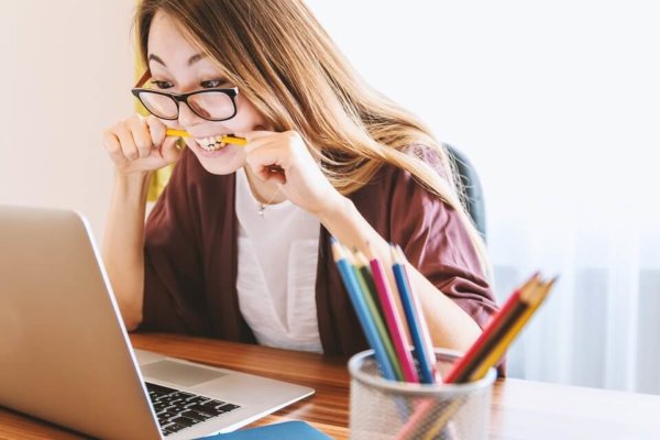 student tips- woman biting her pencil and staring a laptop
