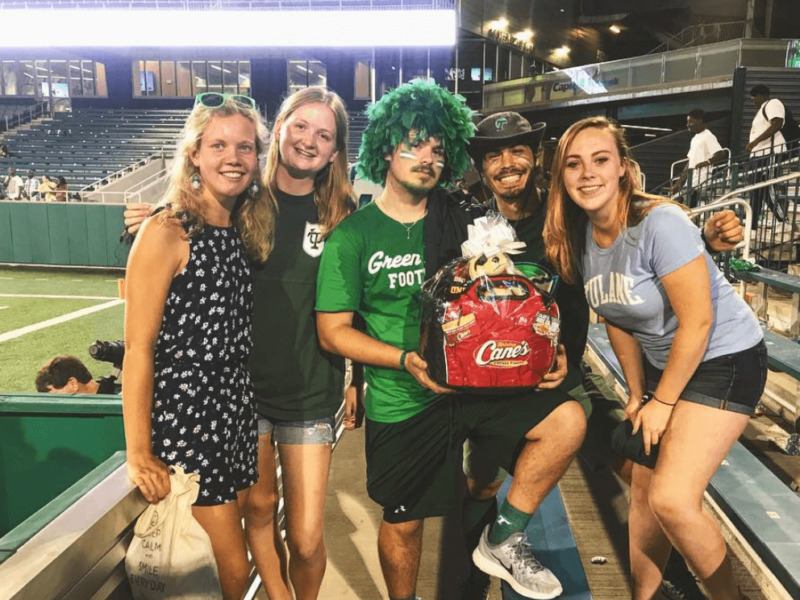 Five Tulane football fans pose with a basket of Canes prizes