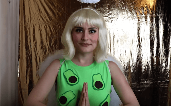 A woman in a green shirt and angel wings/halo halloween costume