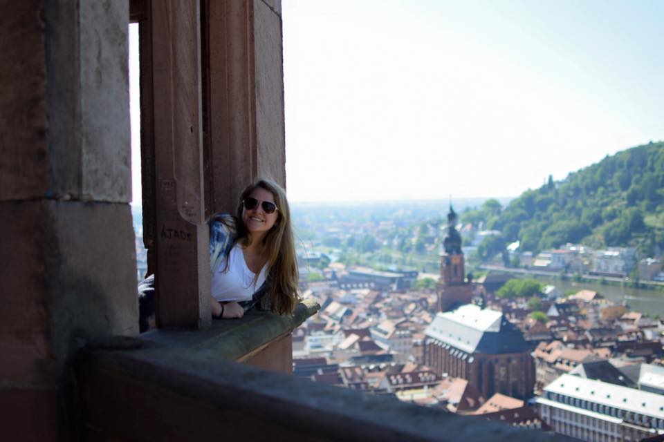 girl looking out window with city below best places to visit in europe