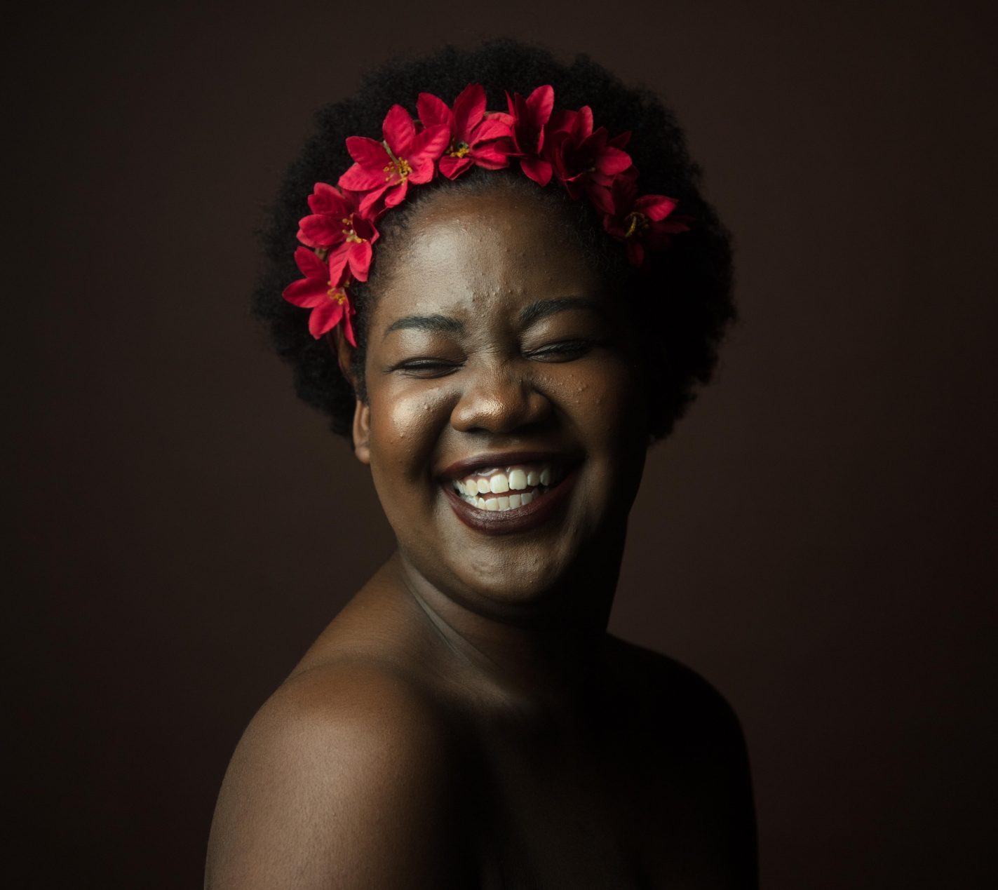 woman with red flowers in hair laughing close up period panties