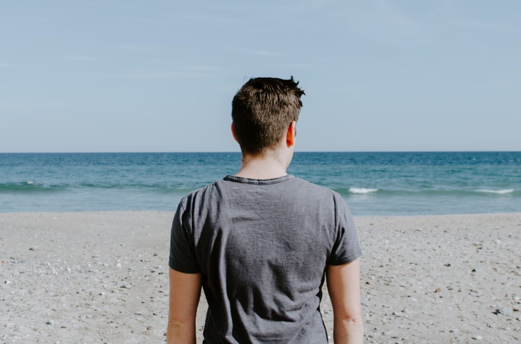 boy gazing out at ocean in reflection