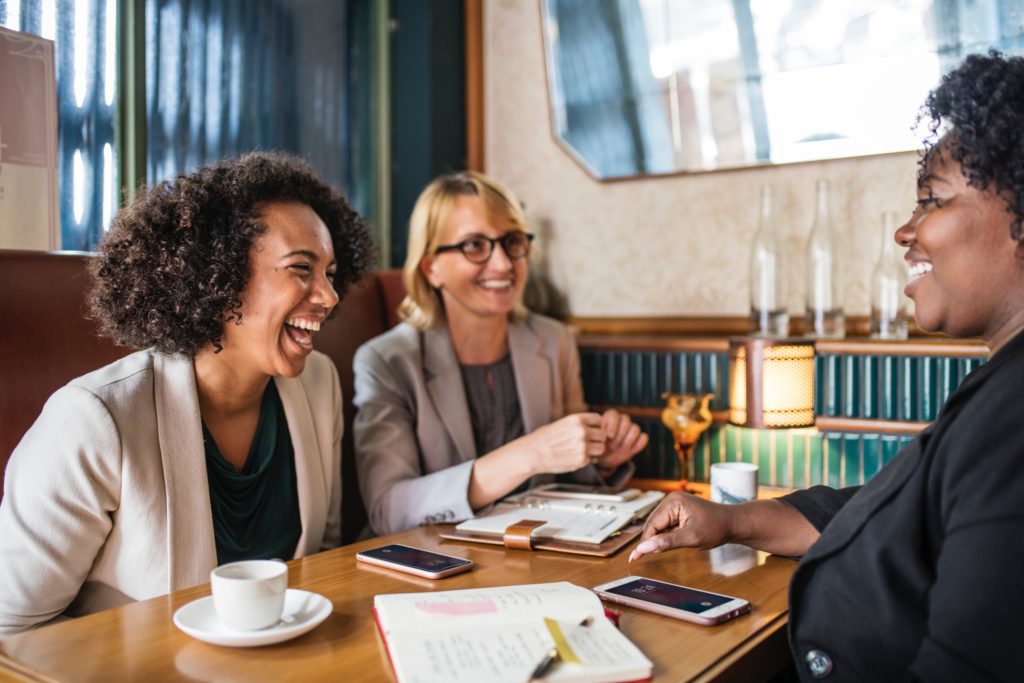 three friends smiling at table interpersonal skills