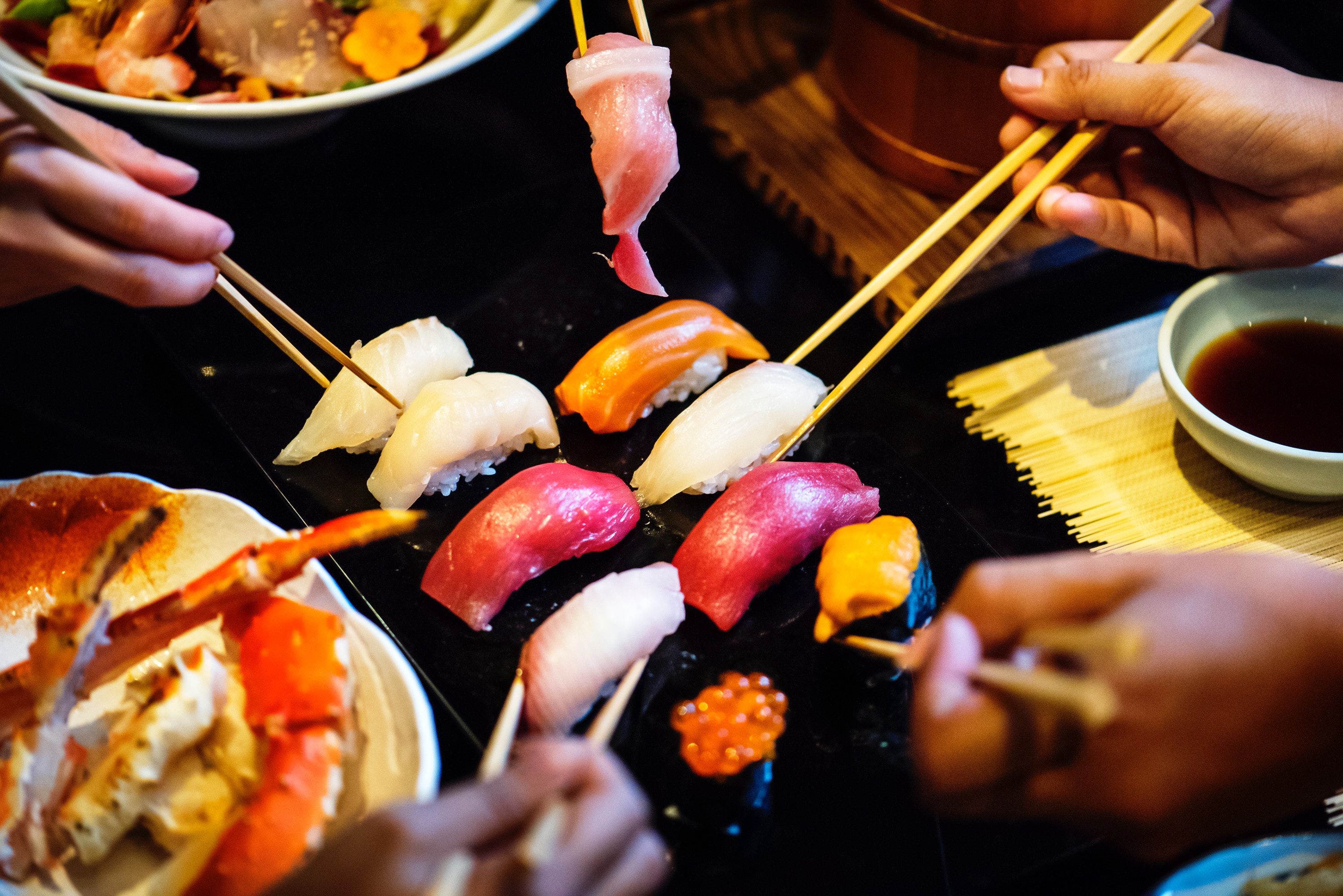 people eating sushi with chopsticks