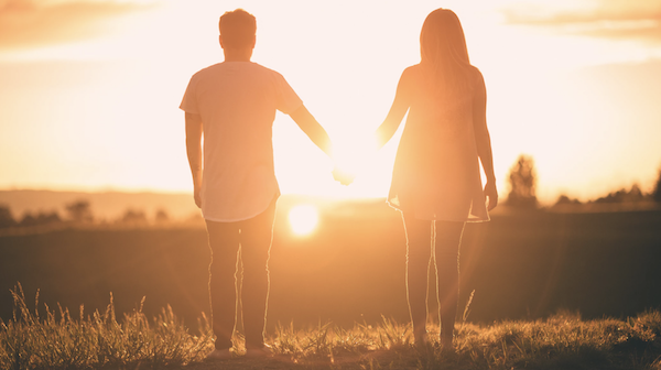 a couple facing the sunset holding hands dating in college