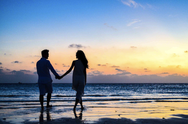 Couple holding hands on the beach dating in college