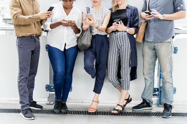 Five people using smartphones dating in college