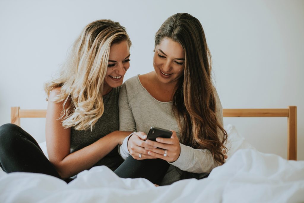 girls in bed laughing at phone