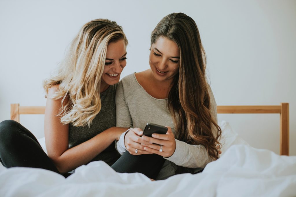 femmes au lit riant au téléphone