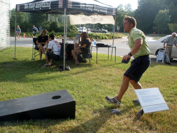 man tossing bean bag into corn hole game