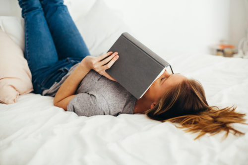 woman laying in bed reading