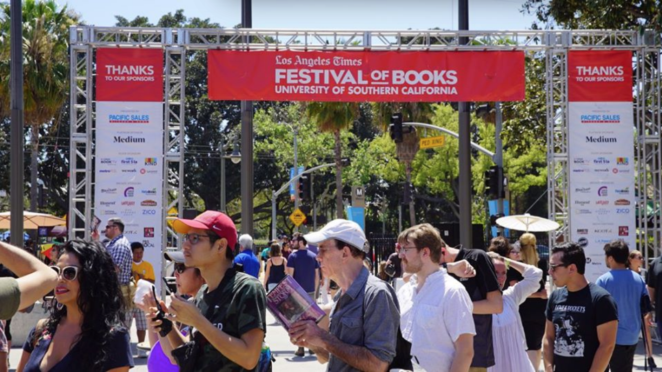 Civilians in line at the L.A Times Festival of Books with a banner in the background. 