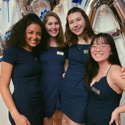 Megan and three other sorority women dressed in navy blue pose together smiling.