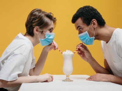 2 people in masks sip from a smoothie together