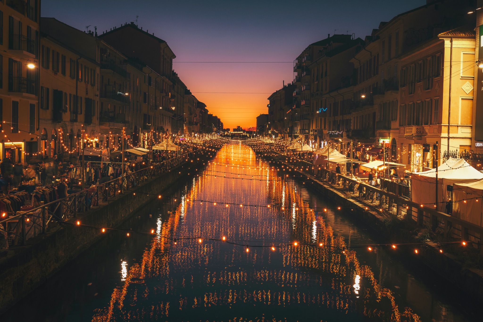 photo of a river in Milan at night with lights strung over it