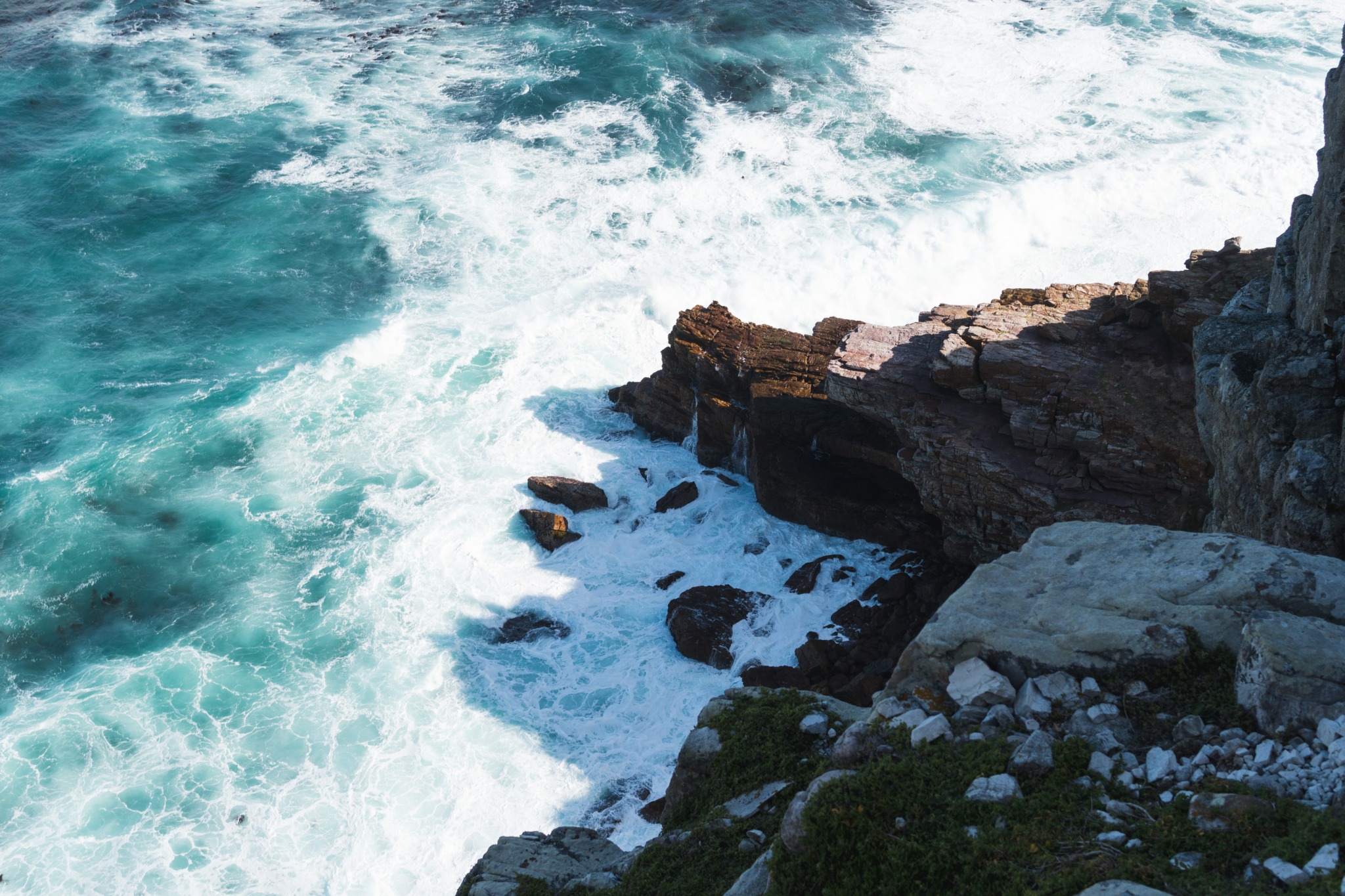 photo overlooking the Cape of Good Hope in South Africa with the ocean water crashing against the jagged rocks.