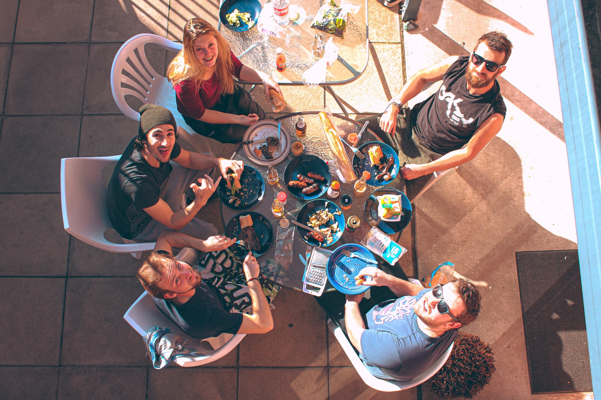 family sits at a table outside for a barbeque