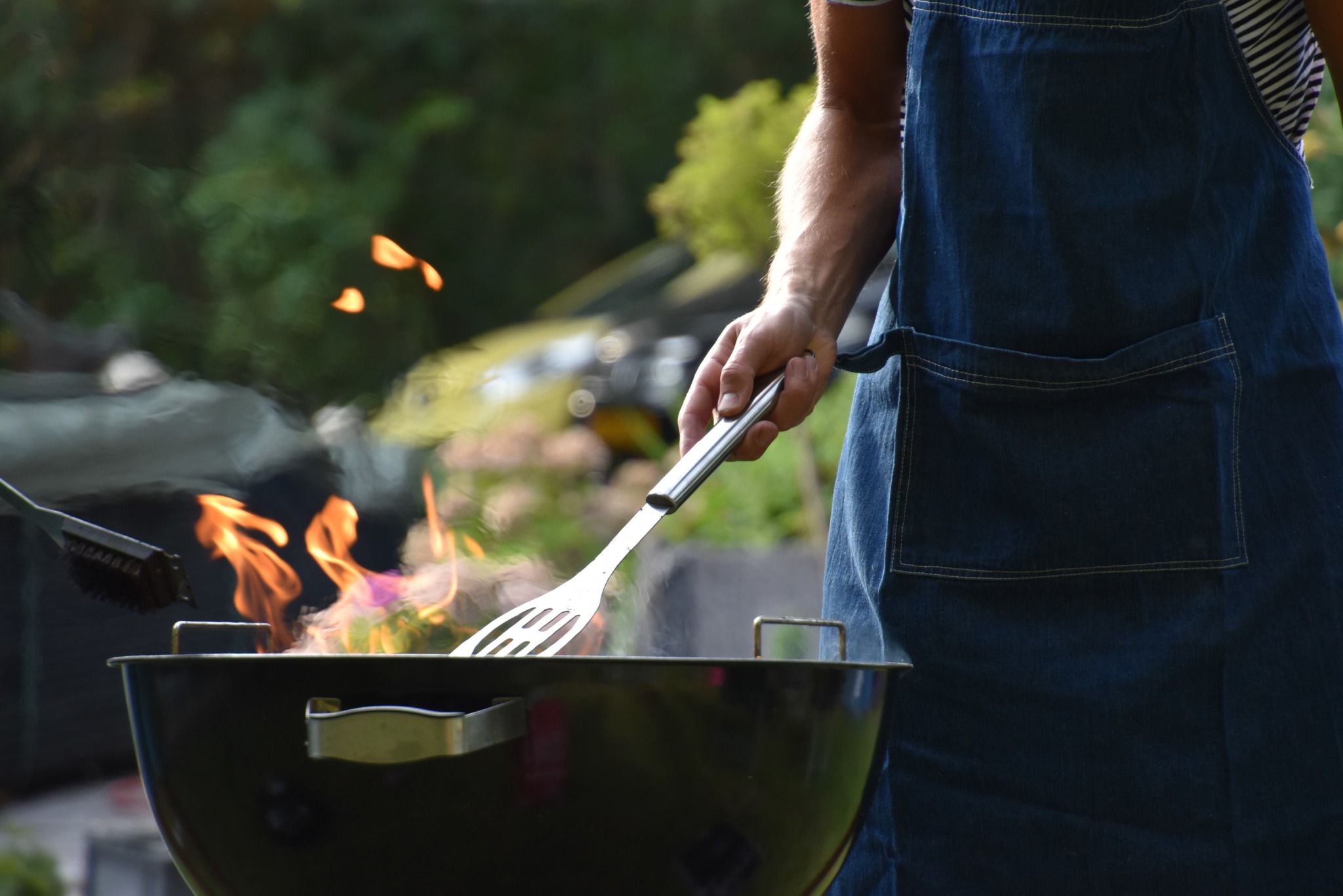 man places spatula on blazing grill outside