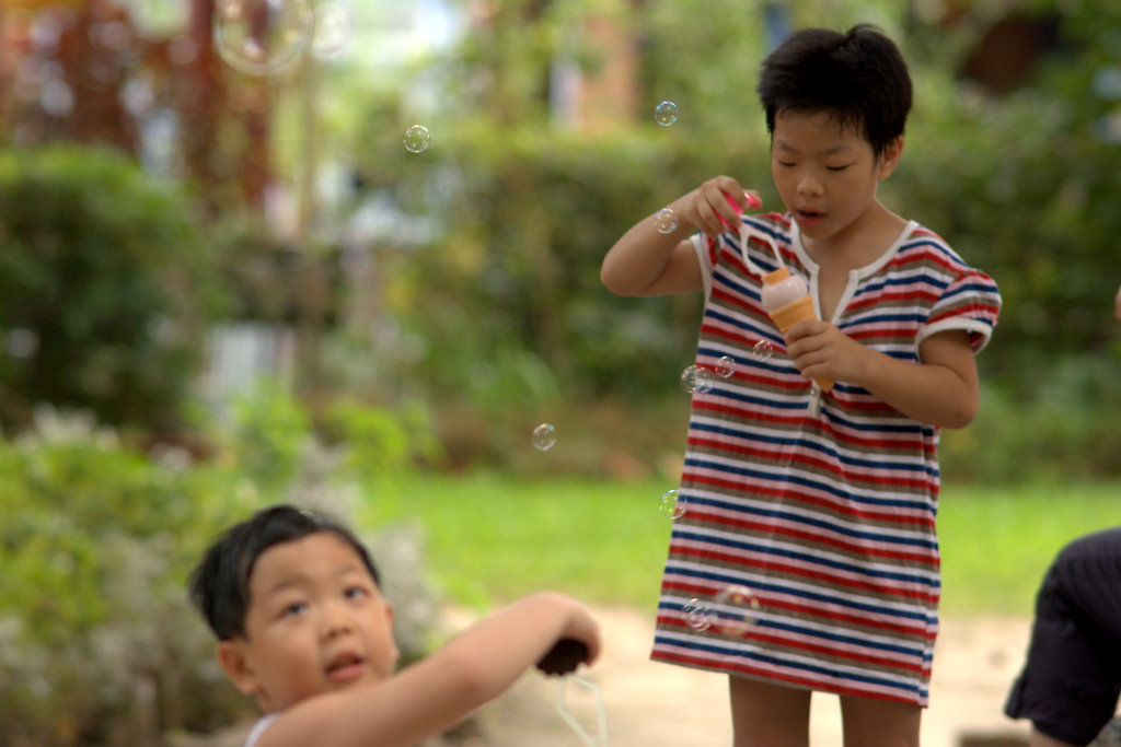 two kids play with bubbles outside