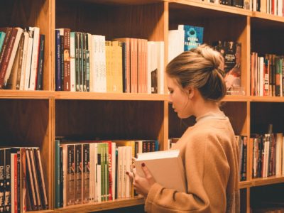 woman looking at stacks of library books
