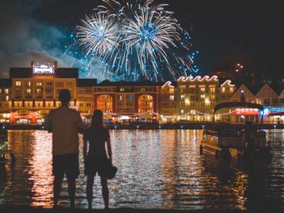 couple stands in front of water while they watch the fireworks