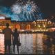 couple stands in front of water while they watch the fireworks