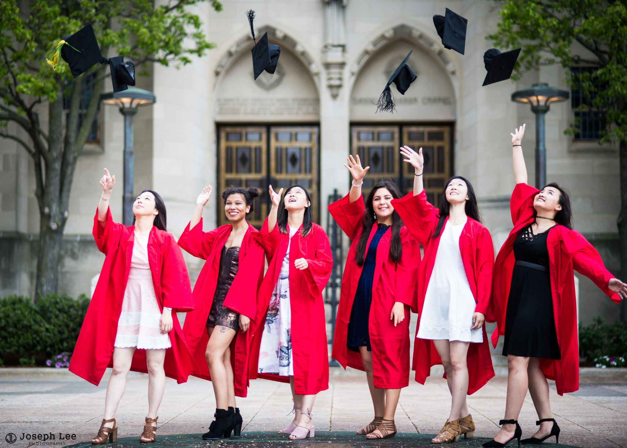 graduates toss their graduation caps while standing on the BU seal