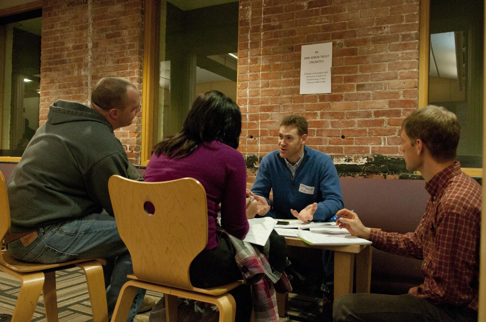 professor talks to students sitting around a desk