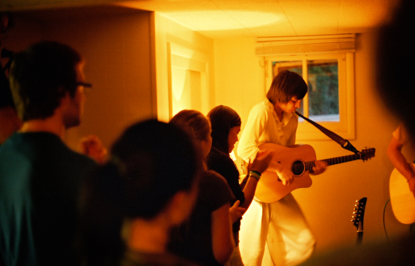 guitarist plays in front of people at a house show