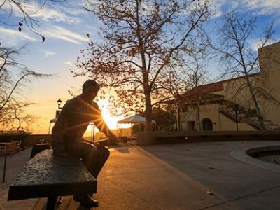 student sitting in Pepperdine plaza at sunset