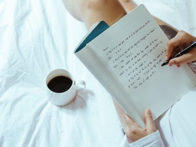 someone writing in a notebook with coffee