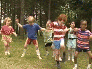 children dancing on green grass in a crazy manner