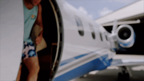 man stepping out of a private jet taking his sunglasses off