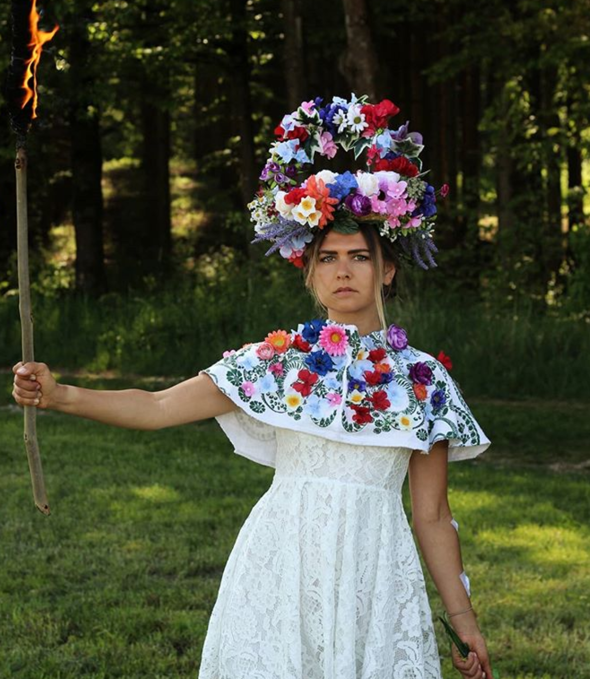 A girl burns a stick dressed in a flowery outfit.