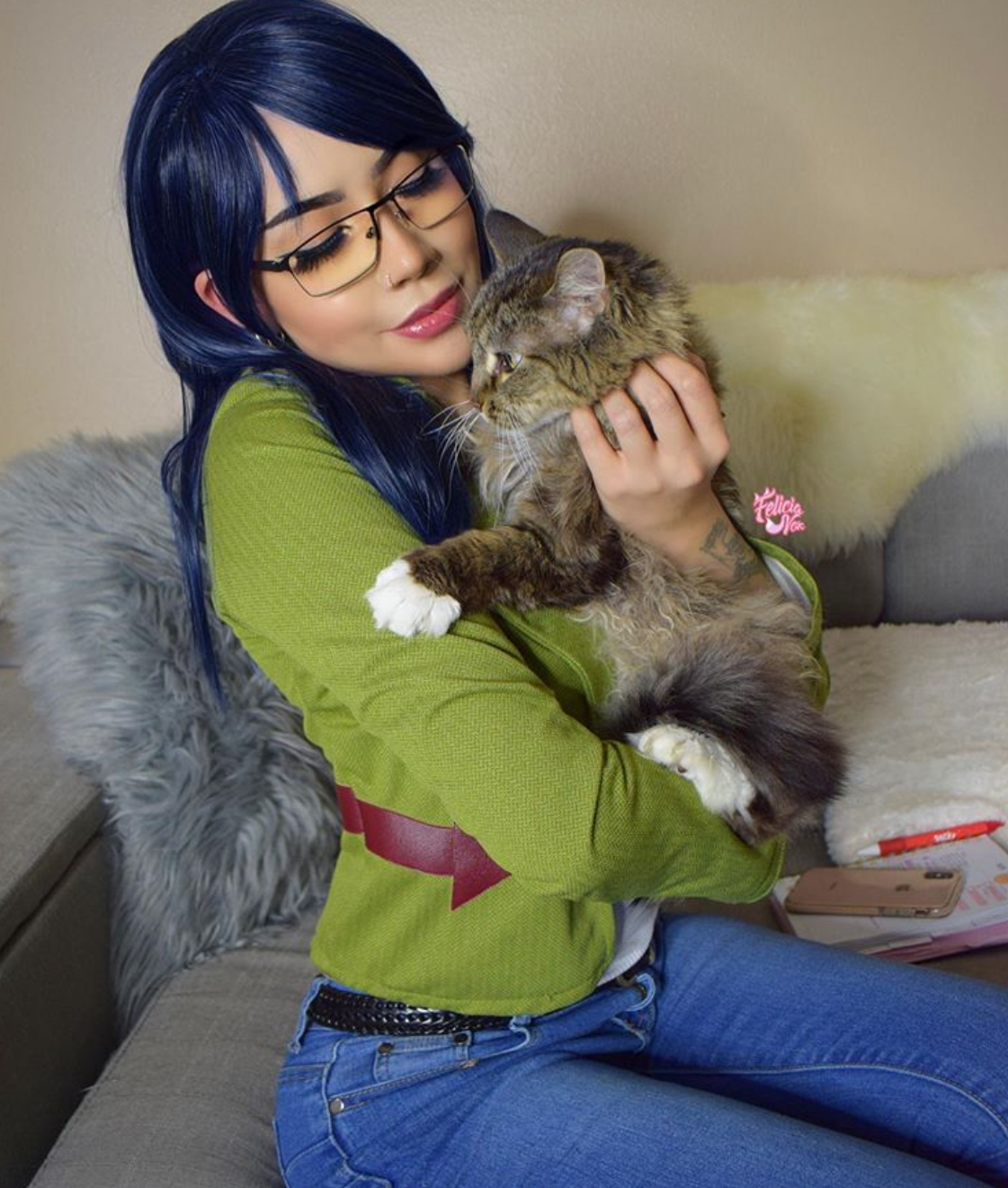 A woman wearing her Diane cosplay cuddles her cat.