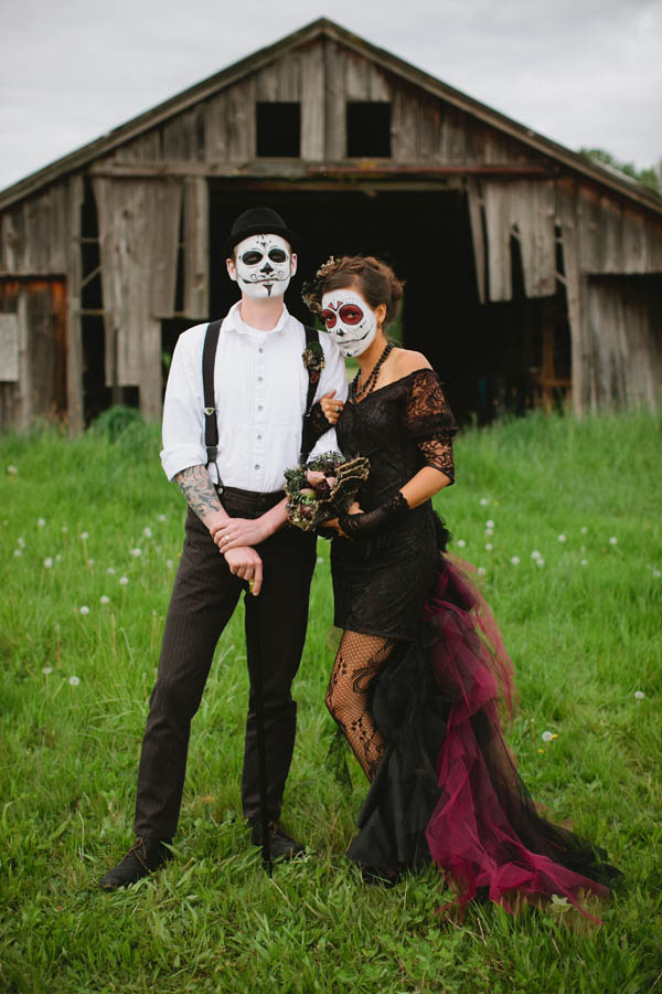 couple in day of the dead makeup in front of a barn