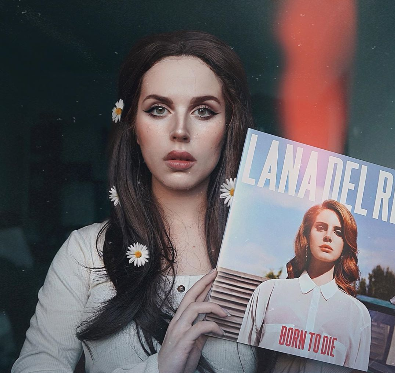 A girl with flowers in her hair and heavy makeup holds a Lana Del Rey album for her costume.