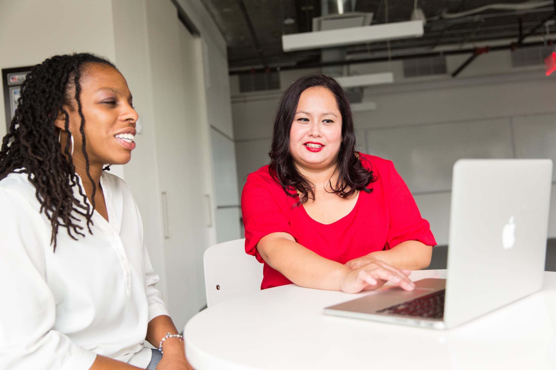 One woman shows another woman something on her laptop.