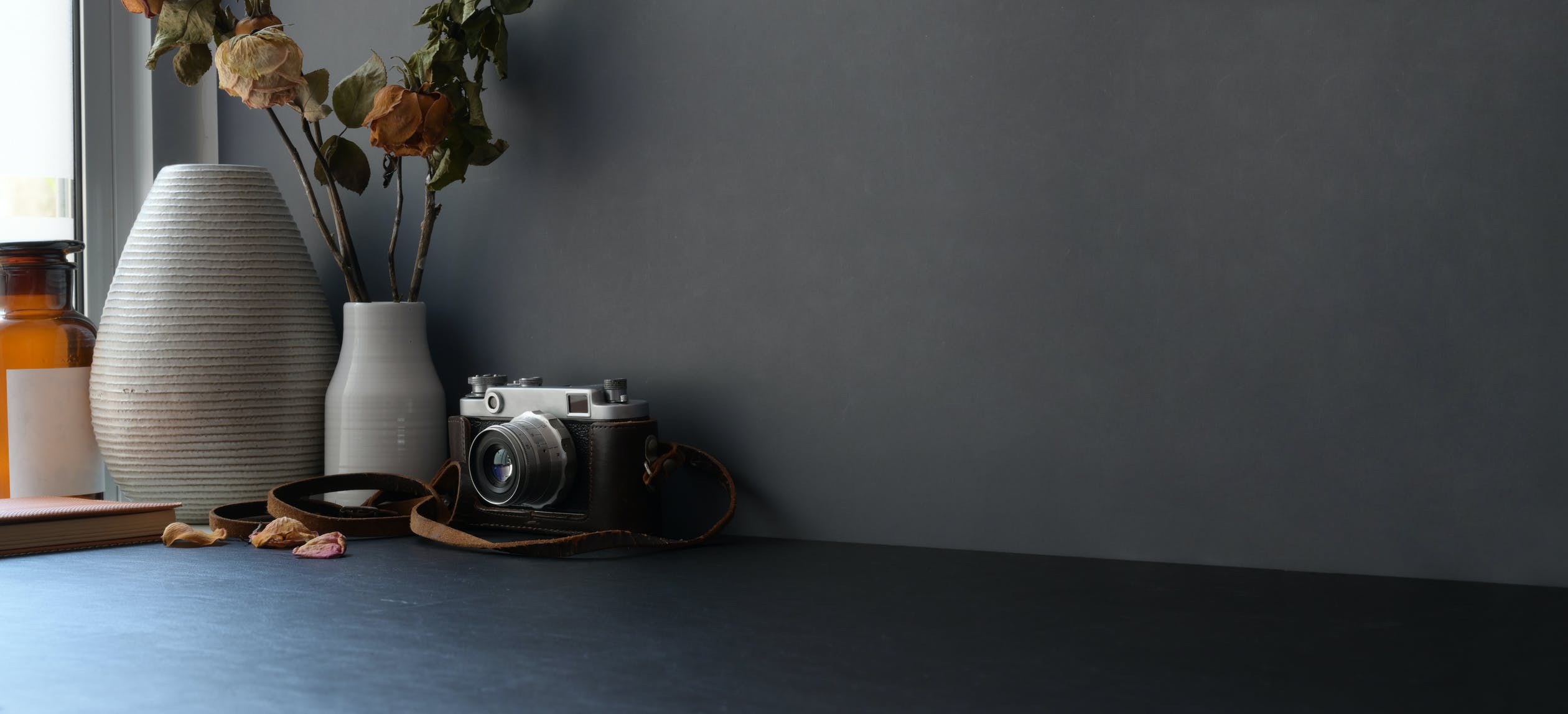 gray wall with a desk, camera, and flower pot