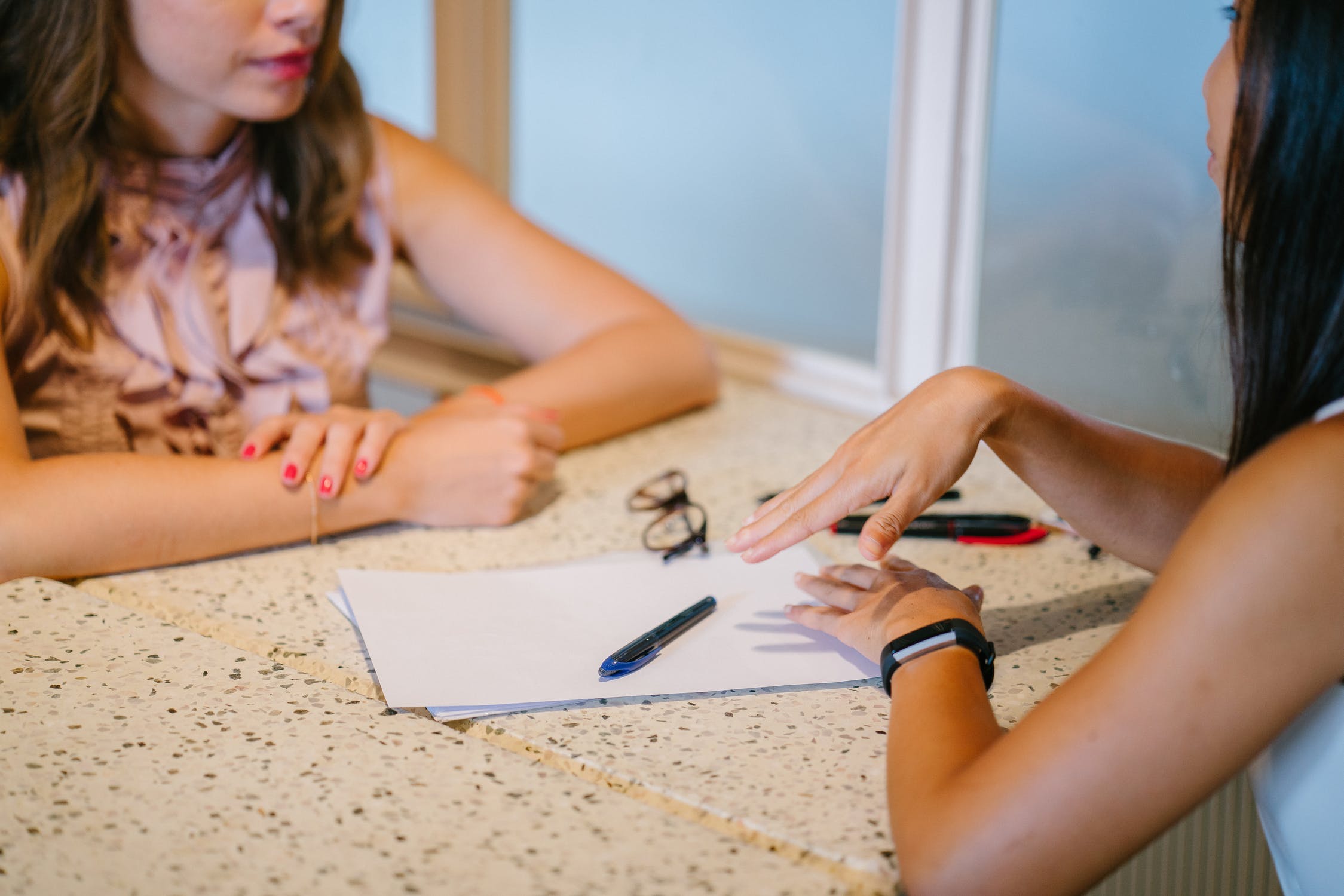 Two women discuss something while at a table.